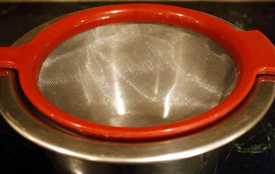 A mesh strainer over a bowl.