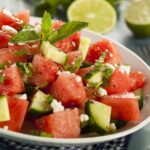 A white bowl filled with a watermelon, cucumber, and mint salad.