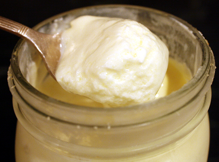 A spoon of creamy homemade yogurt from a jar.