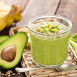 Avocado and banana smoothie with oats with ingredients in glass jar on wooden background.