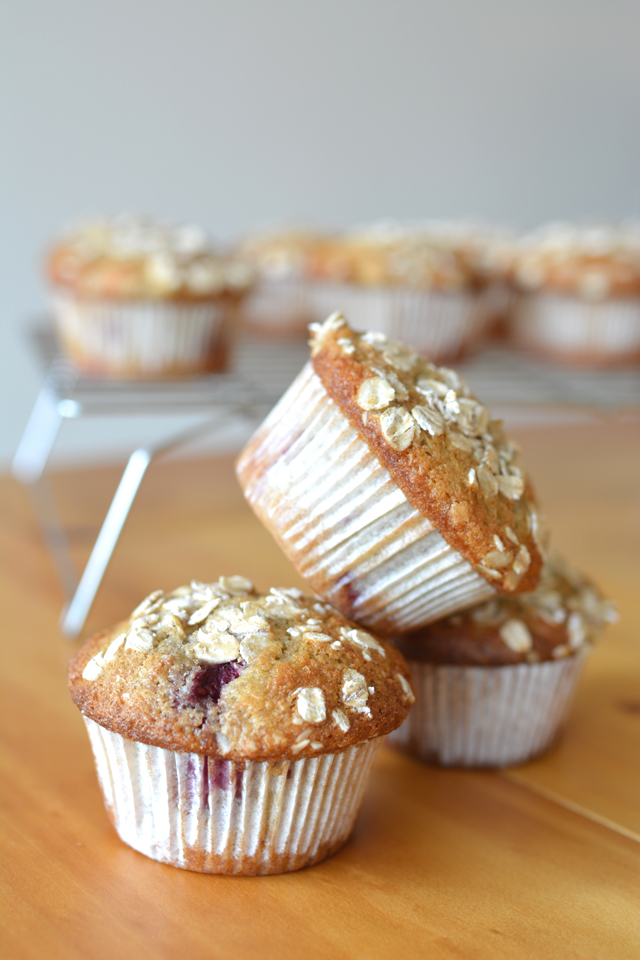 A stack of three delicious raspberry and coconut muffins, topped with oats, showcasing their golden-brown texture and enticing appearance