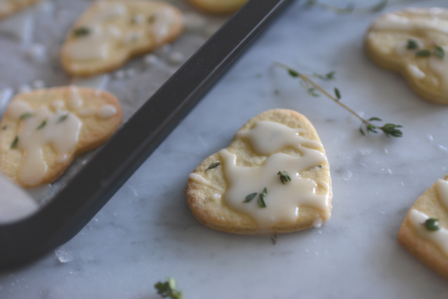 close-up image of heart-shaped Lemon Thyme Mint Cookies, delicately drizzled with icing and adorned with fresh thyme leaves