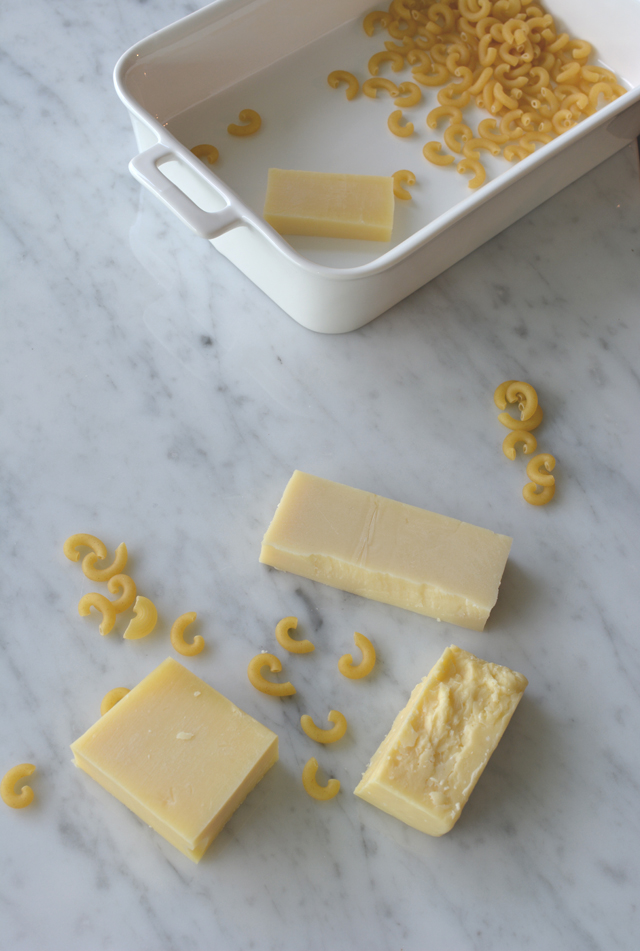 top-down view of macaroni in a rectangular dish with scattered macaroni and three slices of cheddar cheese