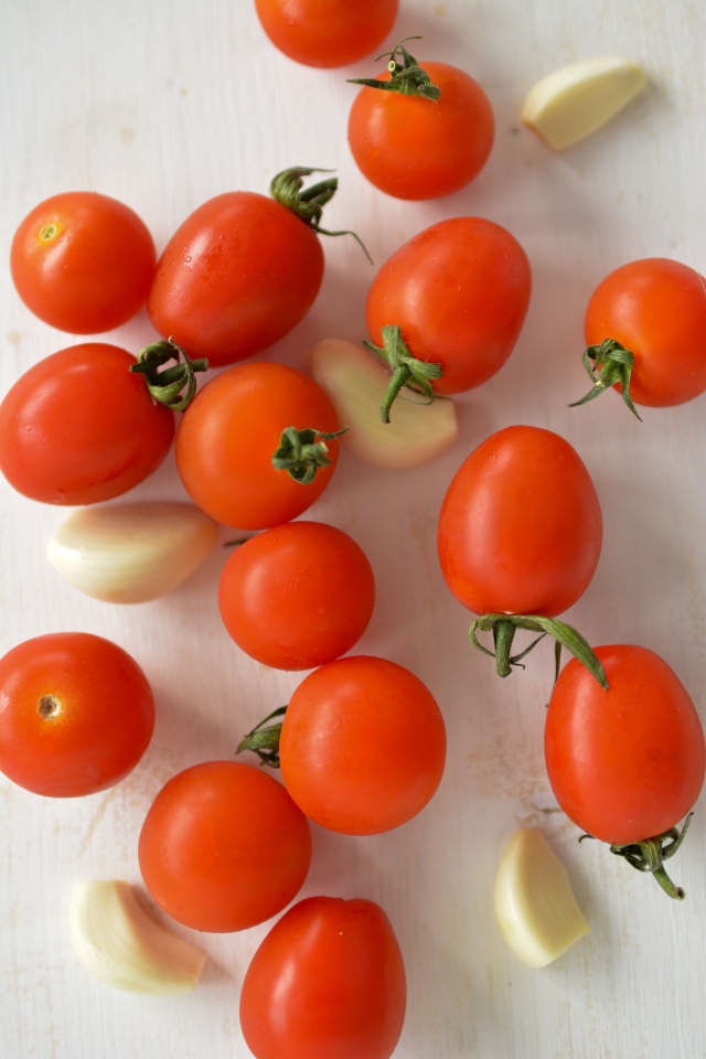 top view image of fresh cherry tomatoes and cloves of garlic