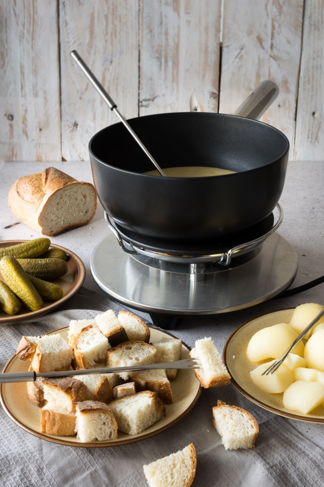Slice of bread in a plate, a cooking pot and another plate with cheese cubes