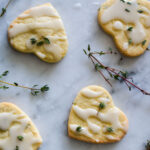 overhead view of four lemon thyme and mint cookies with a drizzle of icing and garnished with fresh thyme leaves