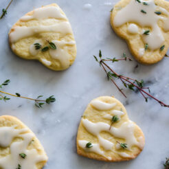 overhead view of four lemon thyme and mint cookies with a drizzle of icing and garnished with fresh thyme leaves