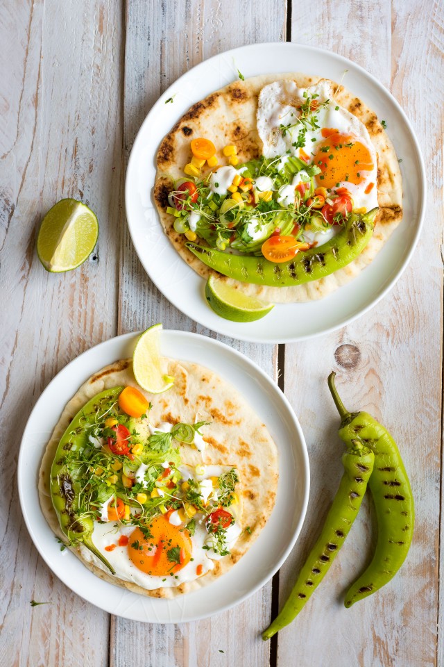 top view image of  two plates with naan bread top with corn, egg and grilled peppers beside the plate