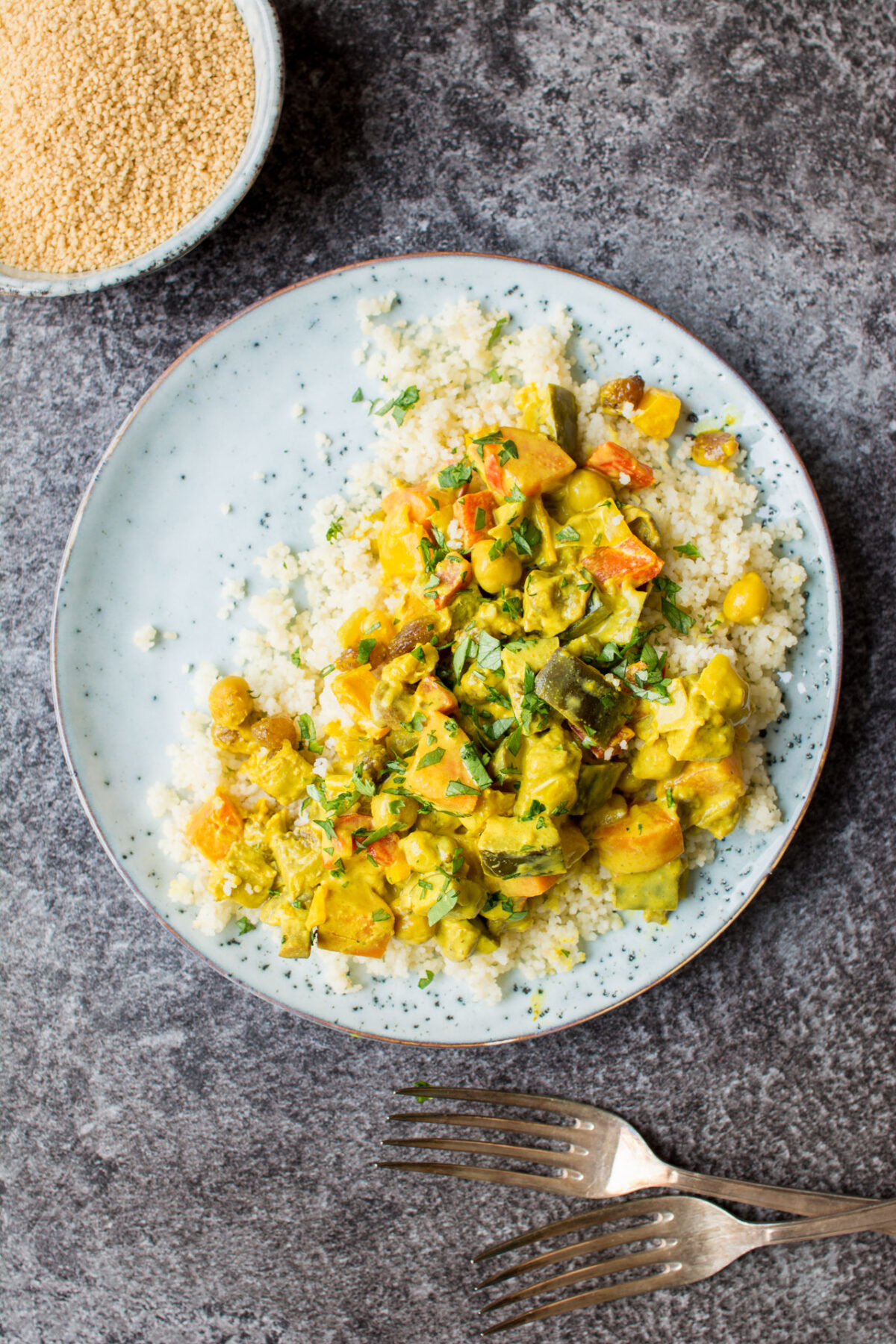 Vegetable curry with turmeric on a white place over a gray background.