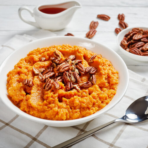 Sweet potato puree topped with pecan nuts in a bowl.
