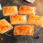 Homemade pop tarts made from scratch cooling off on a wire rack on a table.