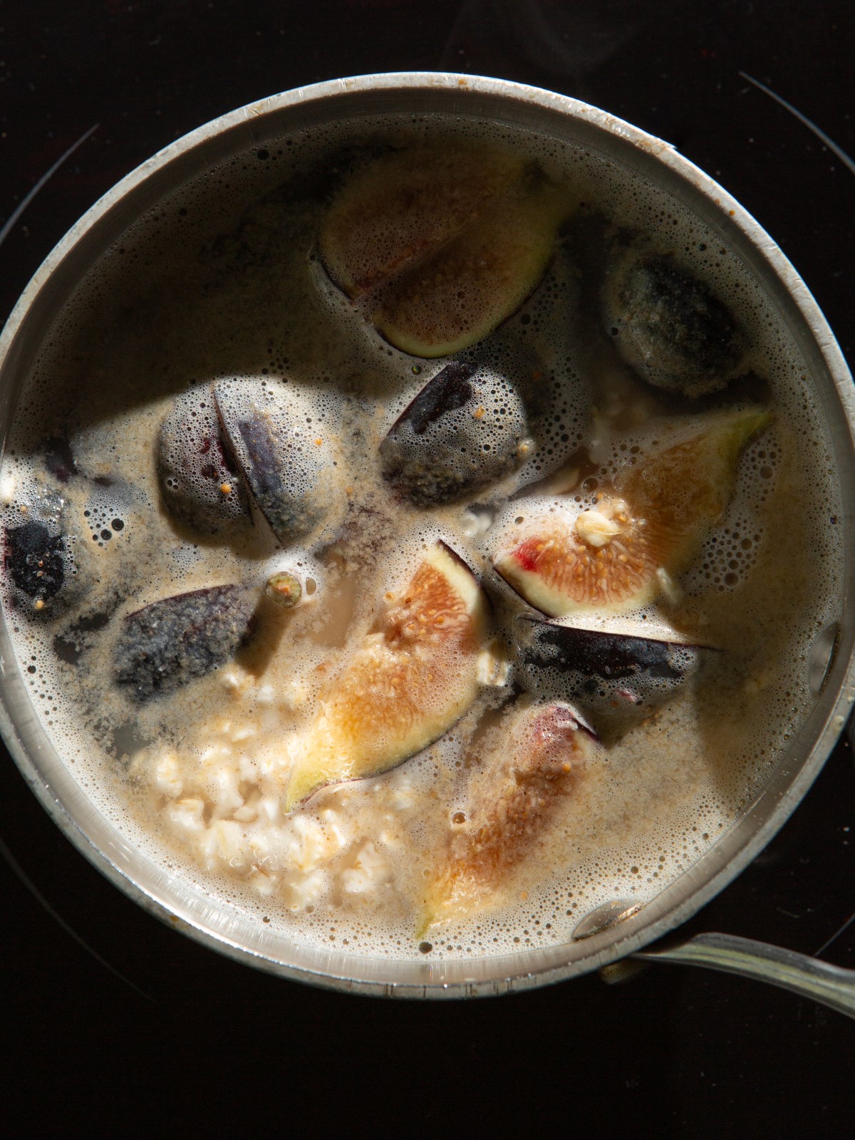 Oatmeal and figs are cooking in a pot.
