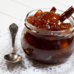 Kumquat marmalade in a glass jar with a spoon.